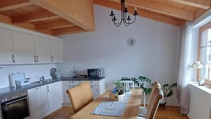 A kitchen with white cabinets, a microwave, and a dining area with a wooden table and chairs.