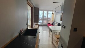 A narrow hallway leading to a dining area with a red sofa and a white table. - 200m from ski slopes, 5th floor, balcony, tv, 43m², Les Arcs (Les Arcs)