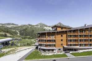 Un hotel de varios pisos con balcones, con montañas al fondo.