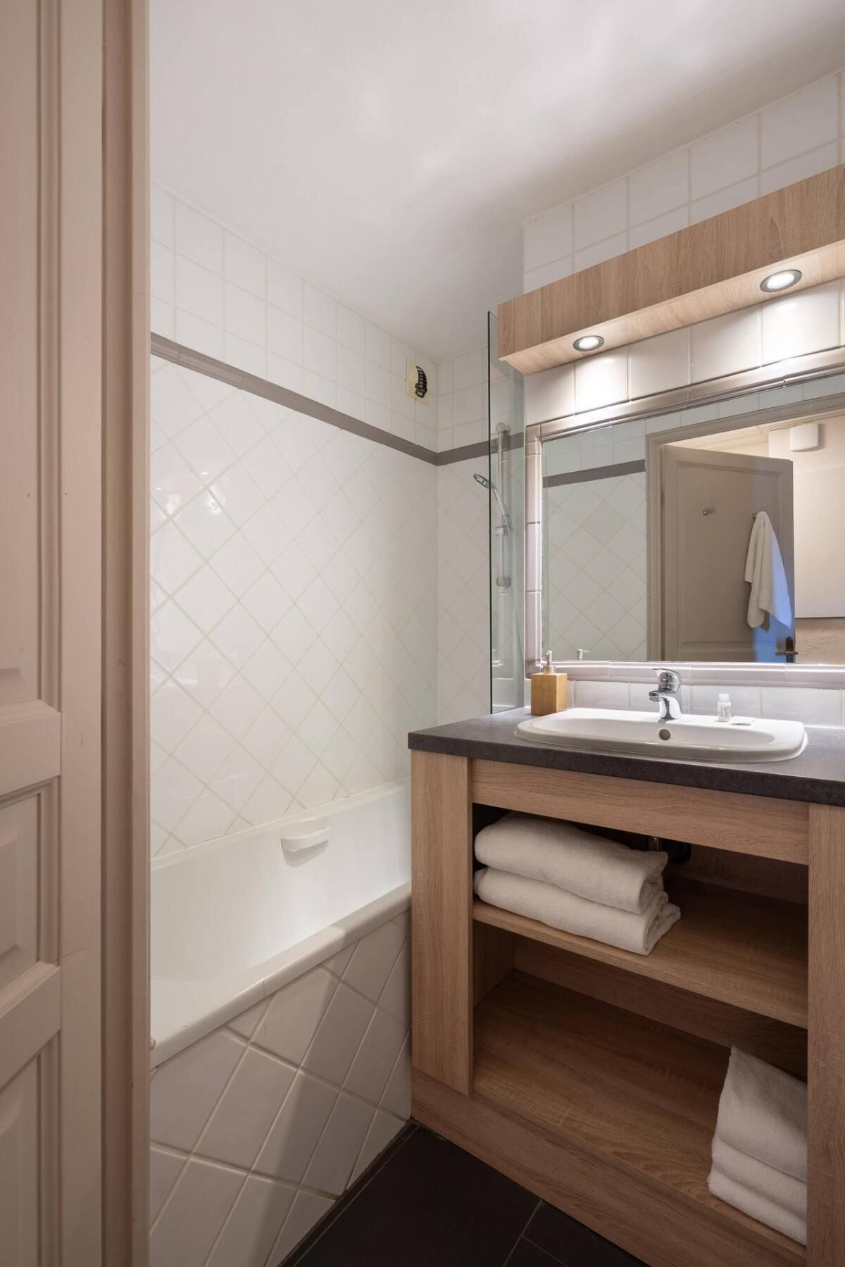A modern bathroom with a glass shower enclosure, a wooden vanity with a sink, and a mirror above the vanity.