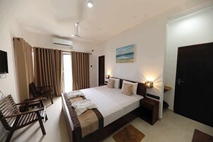Una habitación de hotel con una cama grande, un escritorio, una silla y un cuadro en la pared.