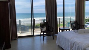 A hotel room with a large balcony, a bed, two chairs, and a table. - Surendra Seaview (Matara)