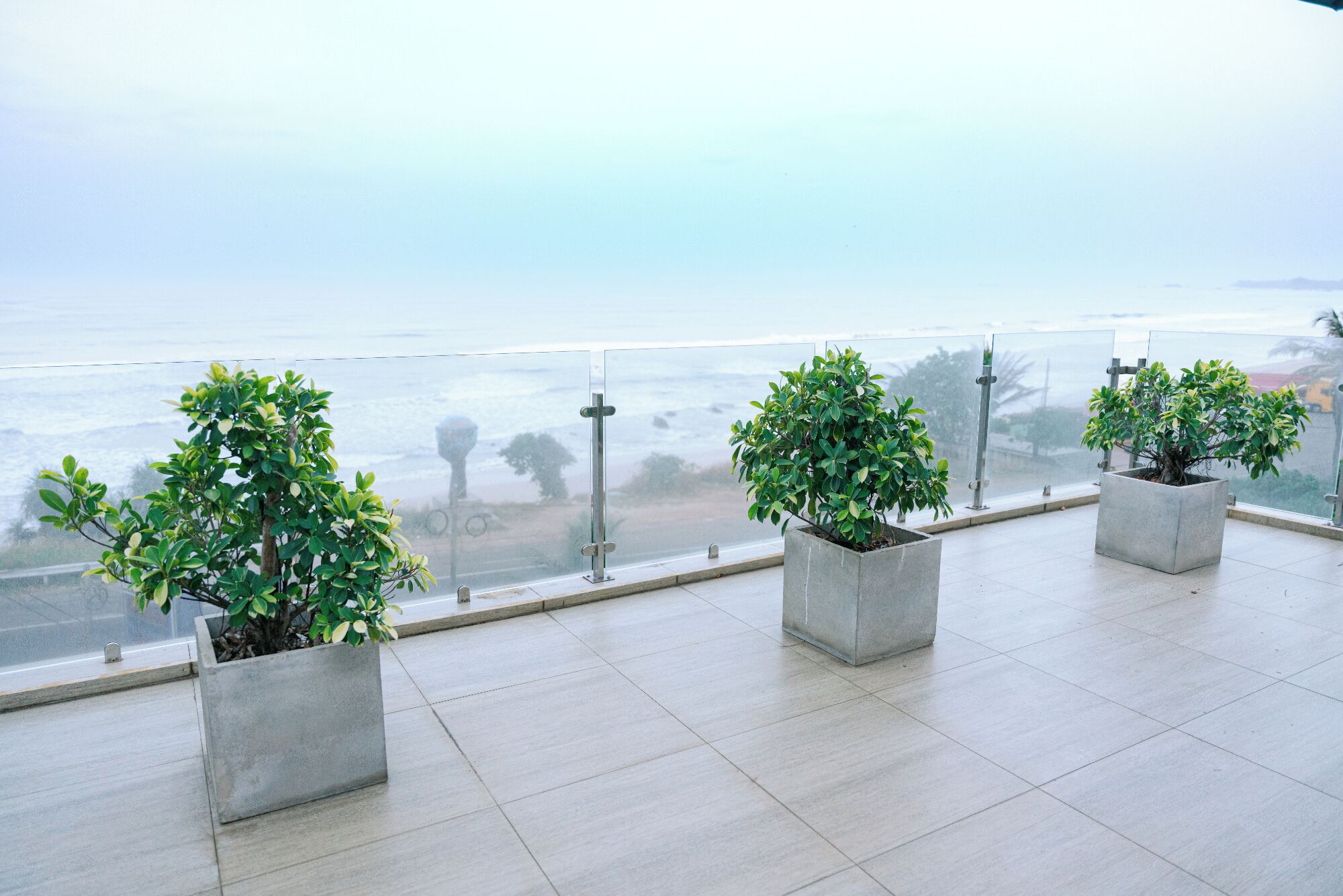 A balcony with potted plants and a view of the ocean.