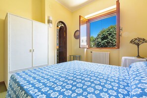 A bedroom with a bed, a wardrobe, a window with a view of greenery, and a radiator. - Terrazze sullo Ionio by BarbarHouse (Santa Caterina)