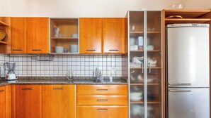 Une cuisine avec des meubles en bois, un réfrigérateur en acier inoxydable et un pare-feu en carrelage.