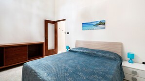 Un dormitorio con una cama, un armario de madera, una mesita de noche y un cuadro colgado en la pared.