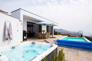 A modern outdoor pool area with a hot tub, a dining set, and a view of the city. - Villa Sundowner - (heated) pool, jacuzzi, sea view (Prazeres)