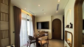 A modern dining area with a round table, chairs, and a flat-screen TV mounted above. - JB Serviced Apartment Phu Quoc (Phu Quoc)
