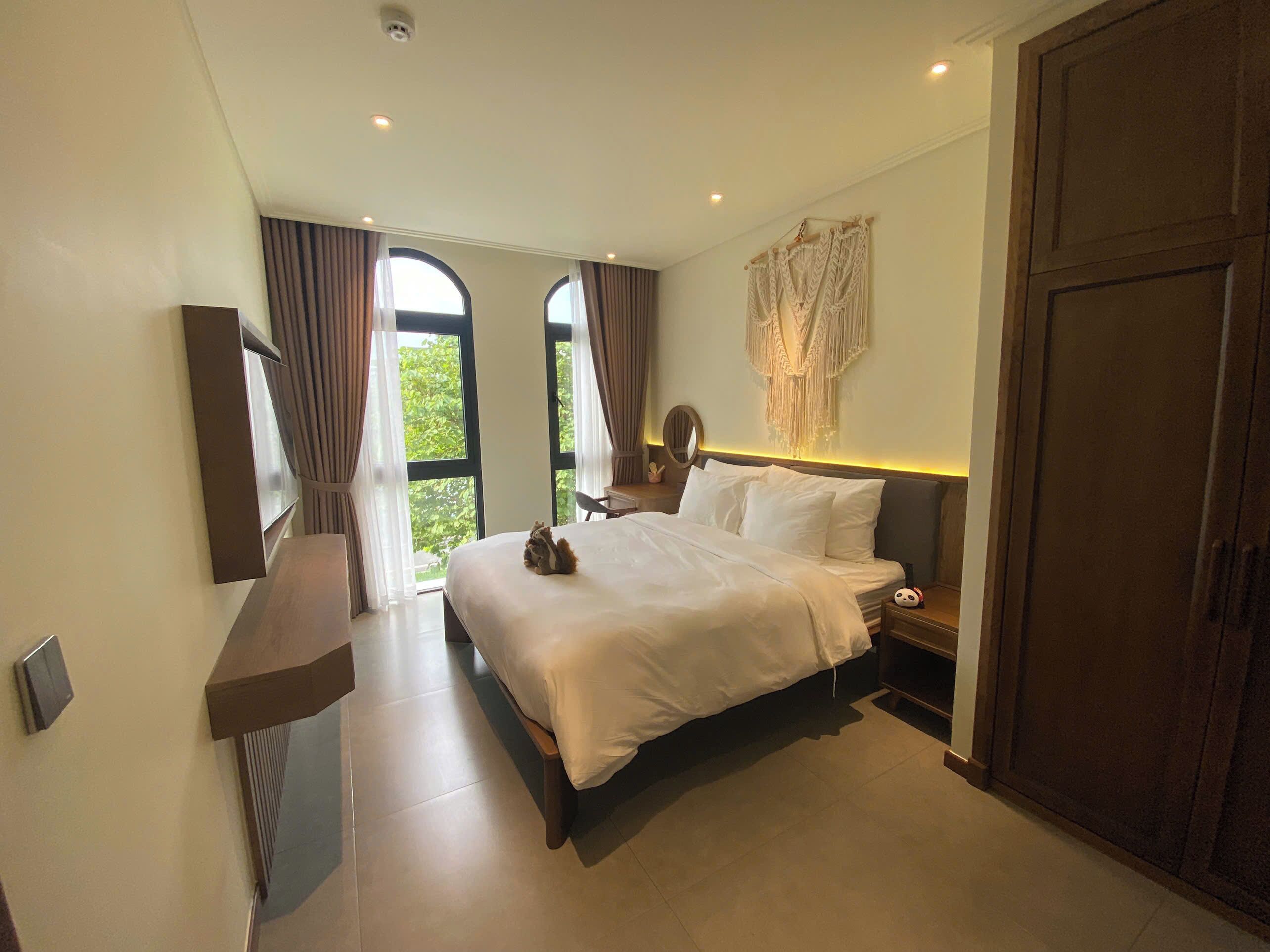 A modern bedroom with a large bed, a bedside table, a mirror, and a wardrobe.