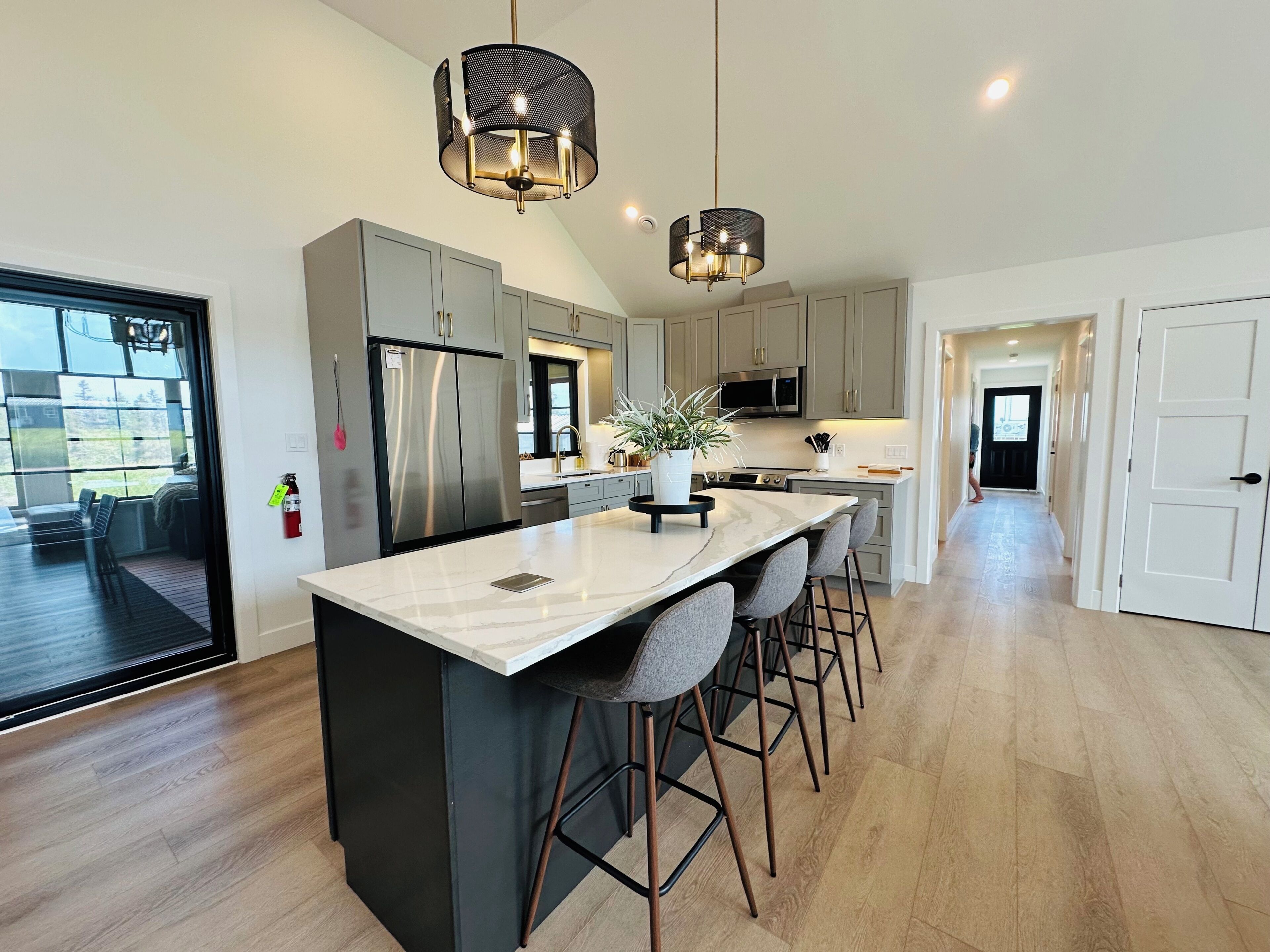 A modern kitchen with a large island, stainless steel appliances, and a pendant light fixture.