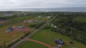 Vista aérea de una zona residencial con casas, una carretera y un cuerpo de agua al fondo.