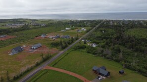 Ovenfra ses et boligområde med huse, en vej og et vandareal i baggrunden.