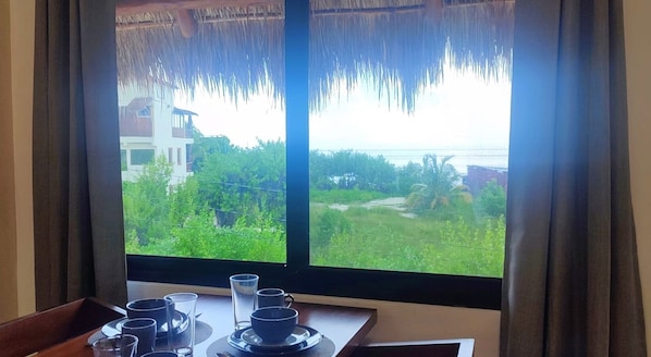 A room with a large window overlooking a lush green landscape and a building in the distance.