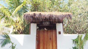 Une porte en bois surmontée d’un petit toit de chaume, un mur blanc et une enseigne portant le chiffre « 2 ».