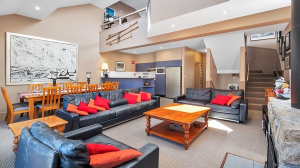 A spacious living area with a dining set, sofas, and a kitchen in the background.