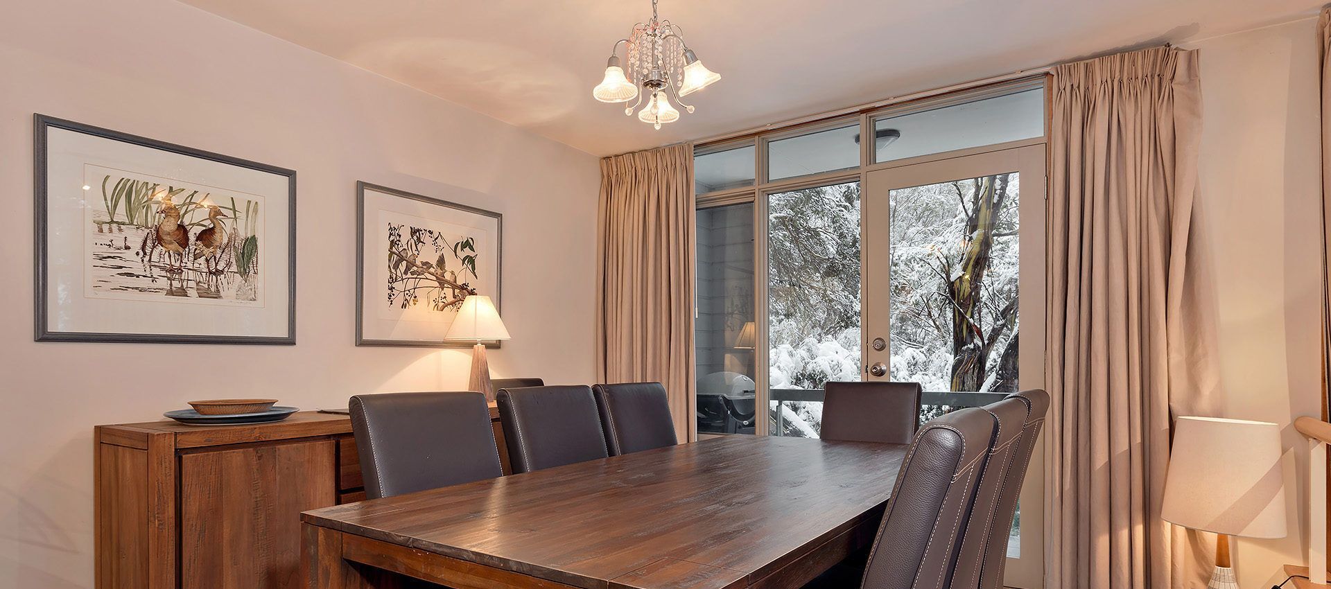 A dining area with a wooden table, chairs, and artwork on the walls.