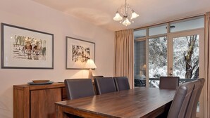 A dining area with a wooden table, chairs, and artwork on the walls.