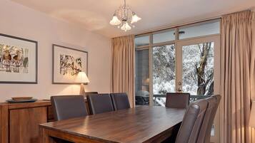 A dining area with a wooden table, chairs, and artwork on the walls.