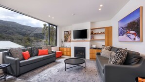 A modern living room with a large window, a fireplace, and a flat-screen TV.