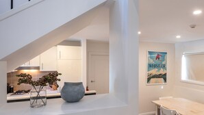 A modern kitchen with a built-in oven, a dining area with a table and chairs, and a staircase leading to an upper level. - Blues Air 4 - Woodridge (Woodridge)