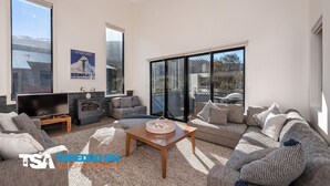 A spacious living room with a large sofa set, a television, and a fireplace. - Blues Air 4 - Woodridge (Woodridge)