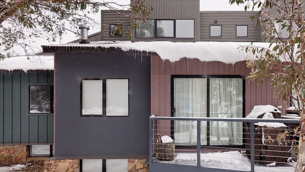 Un bâtiment moderne à deux étages, doté de fondations en pierre, de grandes fenêtres et d’un balcon agrémenté d’une rambarde en métal.