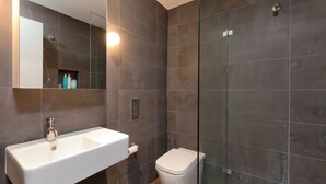 Une salle de bain moderne avec un lavabo blanc, une douche à parois de verre et des toilettes.