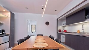 Une cuisine moderne avec une longue table en bois, des appareils électroménagers intégrés et une grande fenêtre.