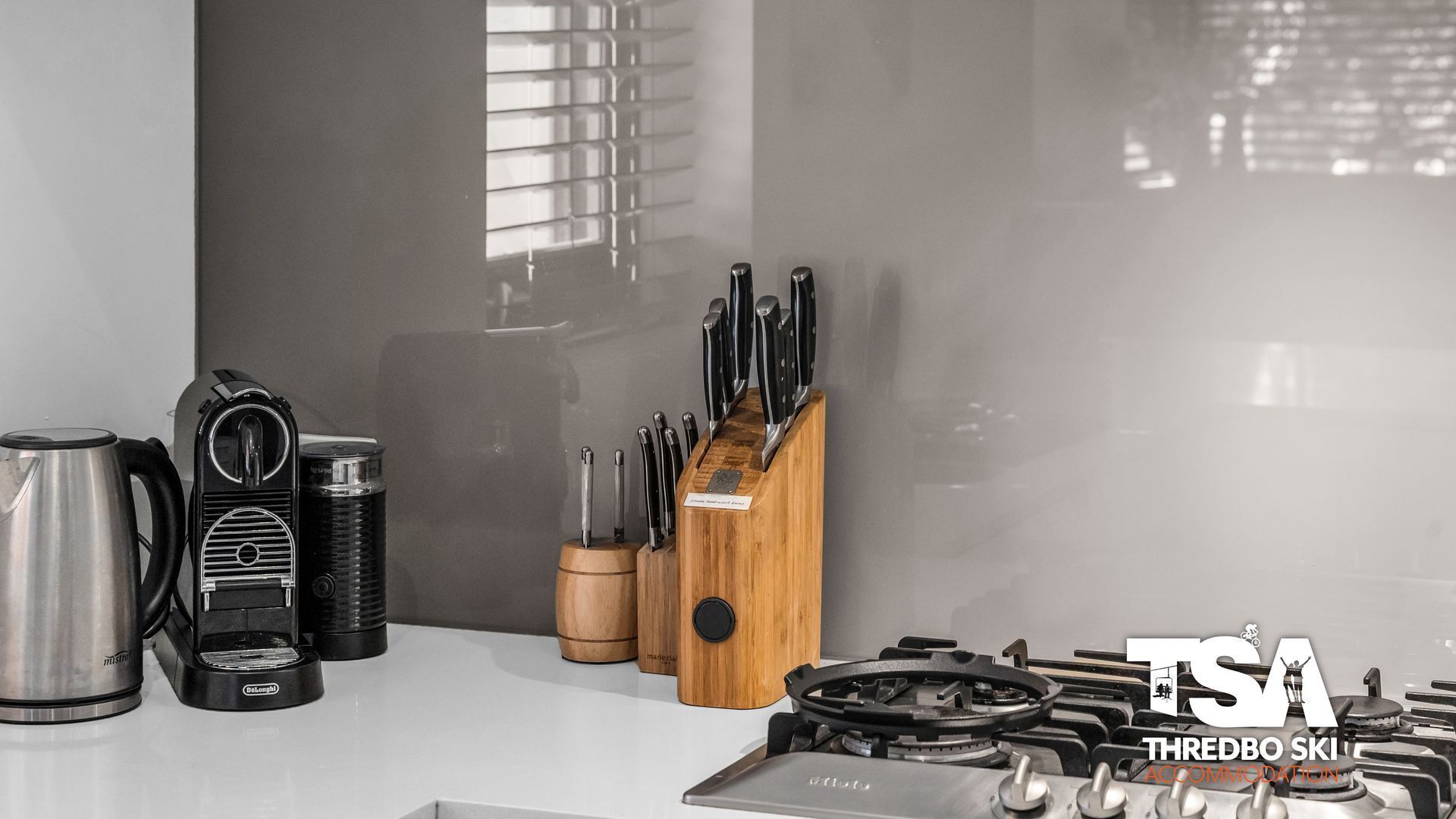 Une cuisine équipée d’une machine à café, d’une bouilloire et d’un ensemble de couteaux.