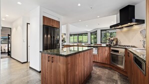 Een moderne keuken met een centraal eiland, roestvrijstalen apparatuur en grote ramen met uitzicht op de omgeving.