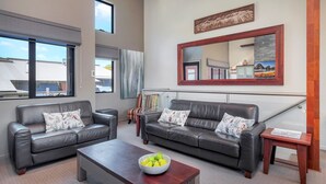A modern living room with two leather sofas, a coffee table, and a large mirror.