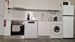 Eine kompakte Küche mit Geschirrspüler, Backofen, Mikrowelle und Waschmaschine.