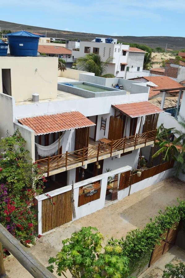 A two-story building with a rooftop pool, a wooden balcony, and a garden area. - Hospedaria Villa Água de Coco (Jijoca de Jericoacoara)