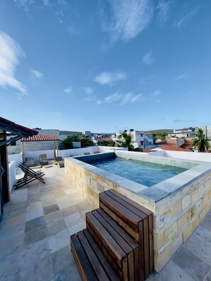 A rooftop swimming pool with a stone deck, lounge chairs, and a pergola. - Hospedaria Villa Água de Coco (Jijoca de Jericoacoara)