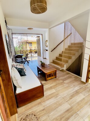 A modern living room with a sofa, a wooden coffee table, and a staircase. - Hospedaria Villa Água de Coco (Jijoca de Jericoacoara)