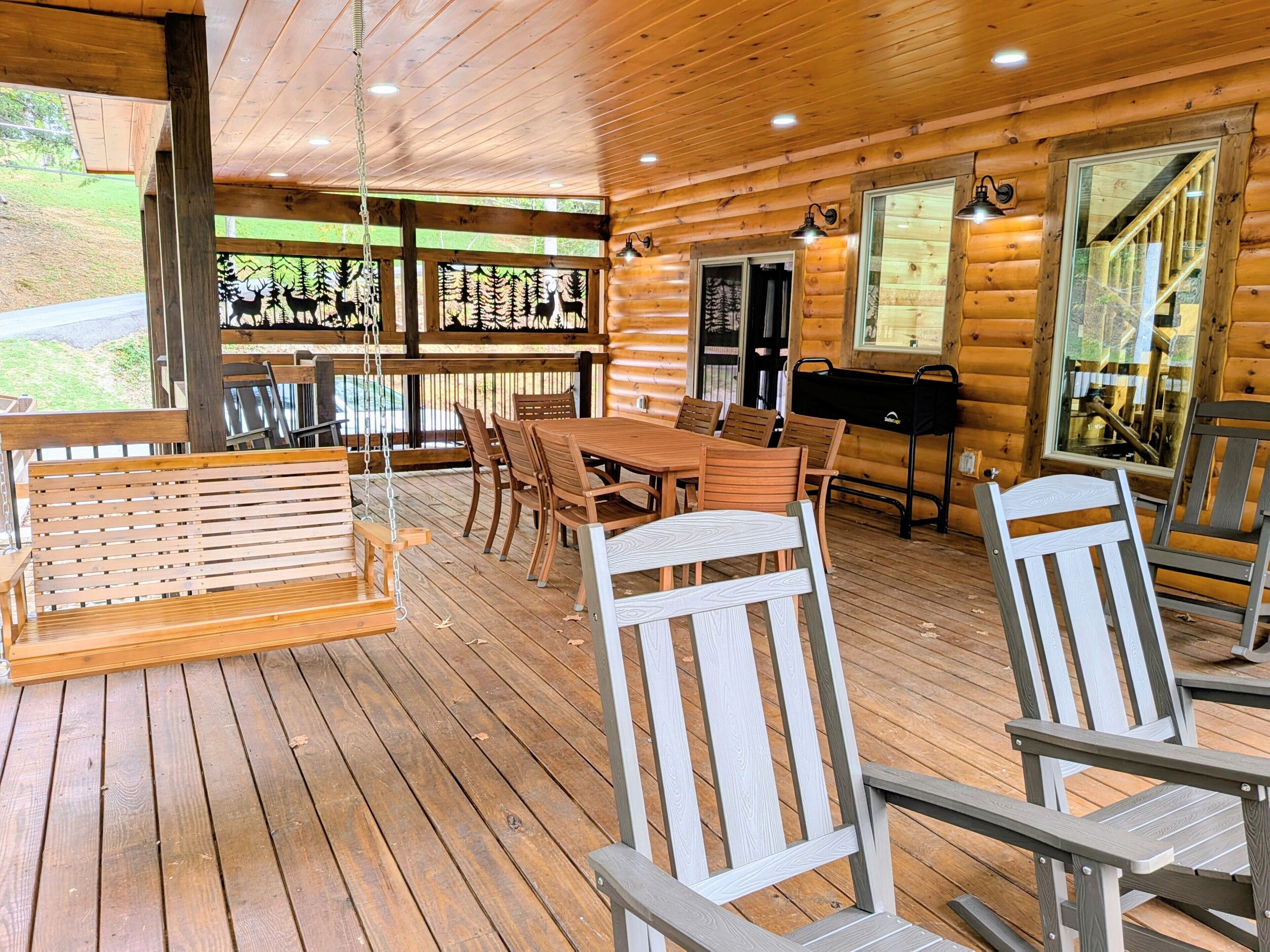 A wooden cabin with a dining area featuring a table and chairs, a hanging swing, and a grill outside.