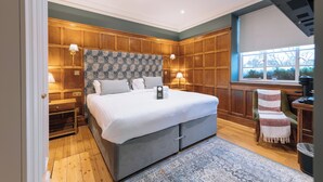 Un dormitorio con una cama grande, paneles de madera, una ventana con vistas y un escritorio con una silla.
