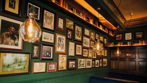 Un restaurante con fotografías enmarcadas en la pared, mesas de madera y cabinas tapizadas en azul.