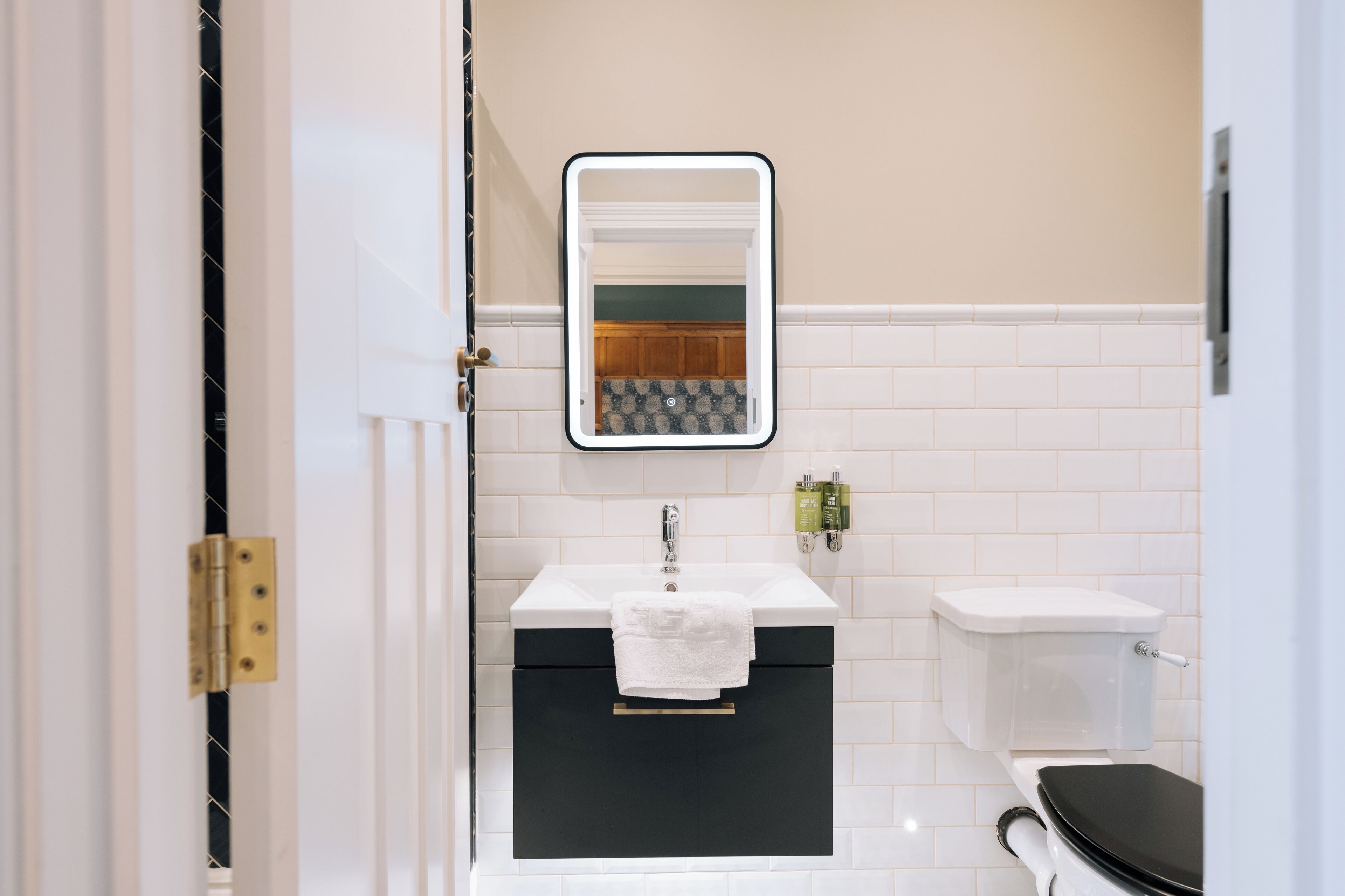 A bathroom with a white sink, black cabinet, and a toilet.