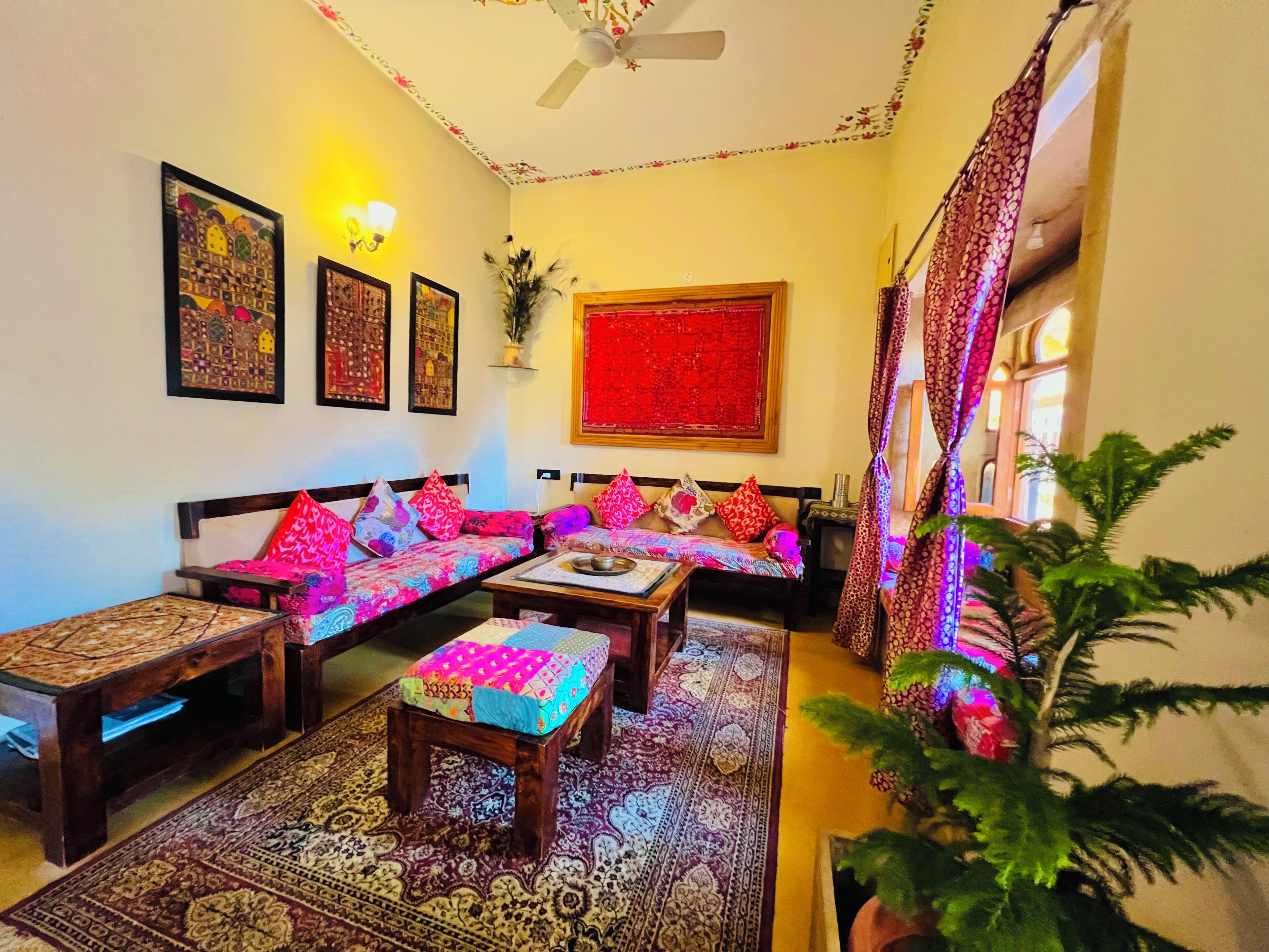 A traditional living room with a sofa set, a coffee table, a patterned rug, and wall art.