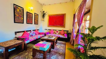 A traditional living room with a sofa set, a coffee table, a patterned rug, and wall art.