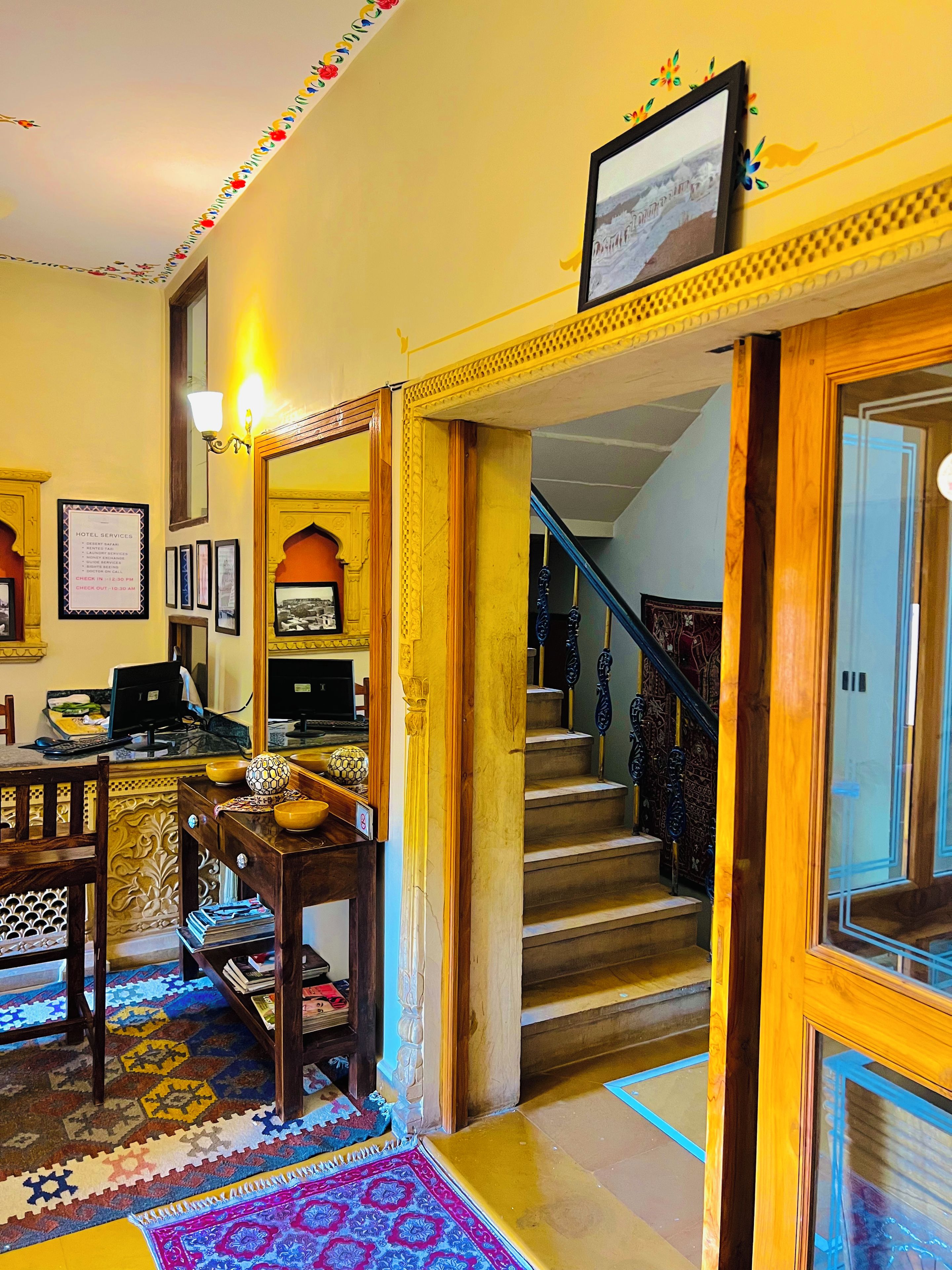 A hotel lobby with a reception desk, a staircase, and a framed picture on the wall.
