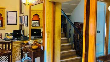 A hotel lobby with a reception desk, a staircase, and a framed picture on the wall.