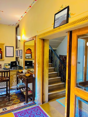 A hotel lobby with a reception desk, a staircase, and a framed picture on the wall. - Jaisan Haveli (Jaisalmer)