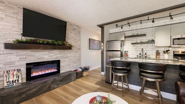 Una cocina moderna con chimenea integrada, una zona de bar con taburetes y una isla grande con lavabo.