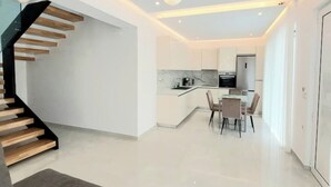 A modern interior with a staircase, a dining area, and a kitchen. - Luxury Villa (Chania)