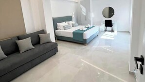 A modern bedroom with a large bed, a sofa, and a mirror. - Luxury Villa (Chania)
