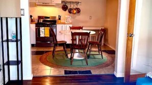 Un espace de vie compact comprenant un coin repas, une kitchenette et un canapé bleu.
