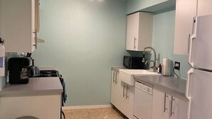 A compact kitchen with a skylight, white cabinets, a microwave, and a refrigerator. - Cozy & Historic | Old Bakery Building Close to Downtown (Albuquerque)
