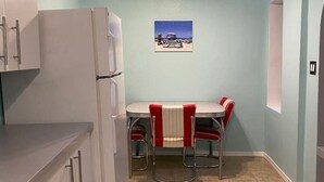 A compact kitchen with a dining area, a small table, and two chairs. - Cozy & Historic | Old Bakery Building Close to Downtown (Albuquerque)